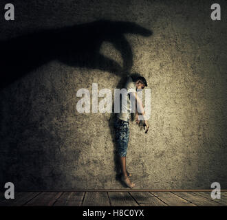 Menschliche Hand Schatten hält einen machtlosen Mann hängen. Konzeptbild als Symbol für Manipulation, Geschäftskontrolle als eine Marionette. Stockfoto