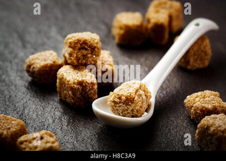 Braune Bio-Zucker Würfel Nahaufnahme auf dunklem Hintergrund Stockfoto