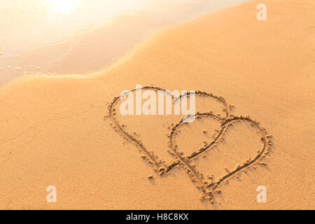 Form der zwei Herzen in den Sand von einem tropischen Strand gezeichnet - Symbol der Liebe, Hochzeitsreise Reisen Stockfoto