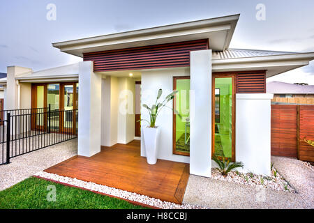 Ein luxuriöses Haus mit einer Fassade, die hat einen Holzboden und eine Beton oder Stein Hof vor. der Himmel hat eine dunkle Farbe. Stockfoto