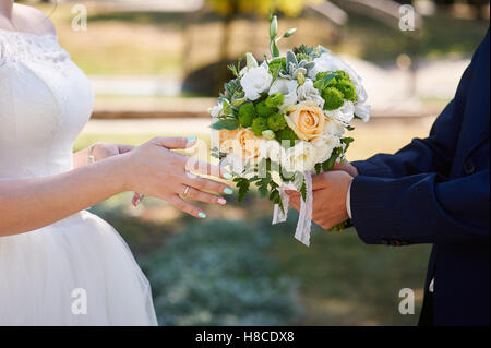 Bräutigam gibt der Braut einen Brautstrauß. Nahaufnahme der Hände Stockfoto