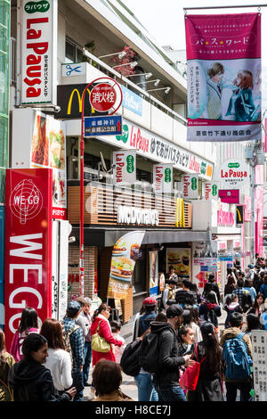 Japan, Tokio, Harajuku. Blick entlang der Fußgängerzone Takeshita Straße mit Menschen am Mittag, von McDonalds und kleine Boutiquen und Geschäften voll. Stockfoto