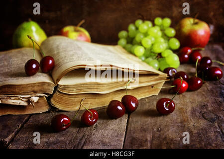 Retro-Buch auf hölzernen Hintergrund und Cherry berry Stockfoto