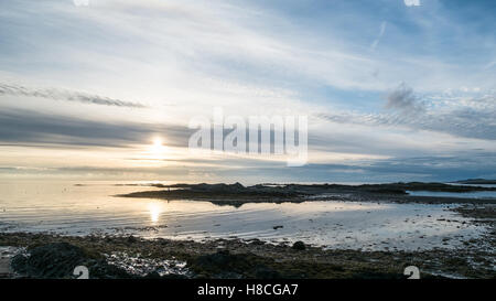 Blick auf das Meer wie die Sonne untergeht über Rhosneigr Strand, frühen Winter, Ebbe, Anglesey, North Wales Stockfoto