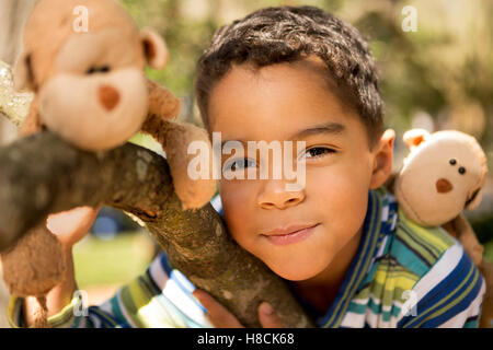 Glückliche kleine Junge spielt in einem Baum. Stockfoto