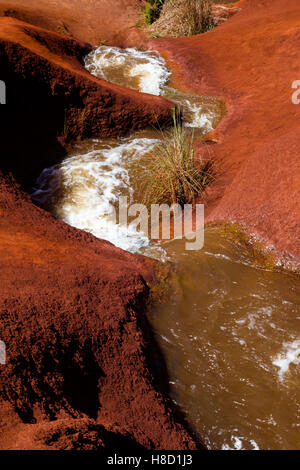 Ein kleiner Wasserfall Graben durch rote Erde in der Waimea Canyon auf Kauai, Hawaii, USA. Stockfoto