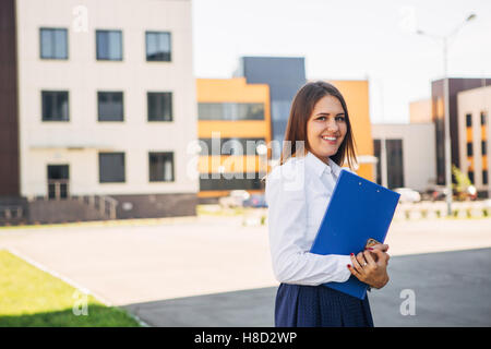 schöne Geschäftsfrau mit einem Ordner vor dem Büro Stockfoto
