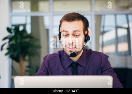 Eine freudige Callcenter-Agent mit seinem Kopfhörer im Fokus Stockfoto