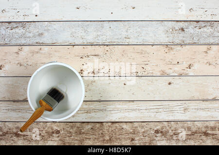Geladenen Pinsel über eine leere weiße Farbe Wasserkocher auf hellen bunten Boden einsteigen gelegt Stockfoto