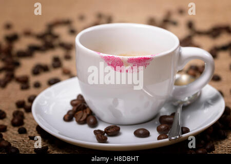 Tasse Kaffee mit Spuren von Lippenstift und Kaffeebohnen um Stockfoto