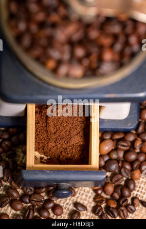 Kaffeebohnen in alte Kaffeemühle und gemahlenen Kaffee auf jute Stockfoto