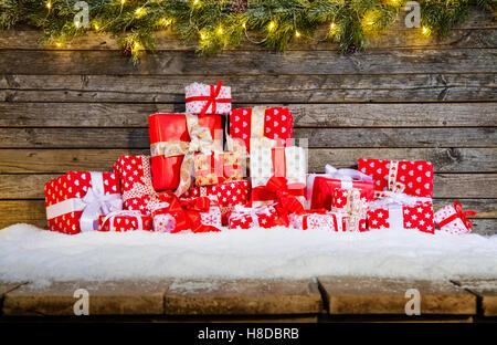 Weihnachten Hintergrund mit Haufen von Geschenken auf Holzbohlen im Schnee gelegt. Tannenzweigen Dekoration an der Spitze Stockfoto