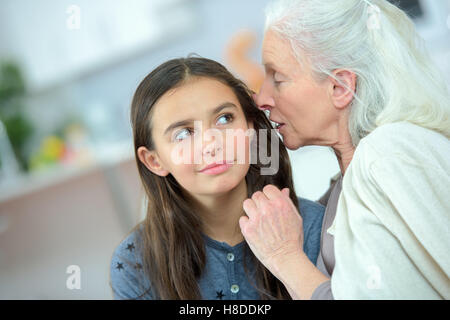 Kleine Mädchen und Oma flüsterte Geheimnisse Stockfoto