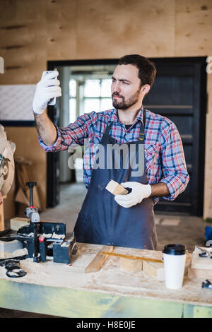 Zimmermann nimmt ein Selbstporträt mit Gehrung sah an seinem Arbeitsplatz Stockfoto