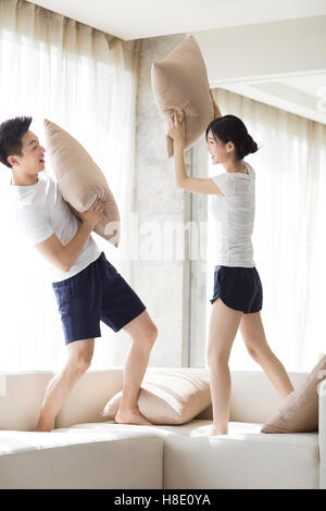 Junge chinesische paar Kissen Kämpfe im Wohnzimmer Stockfoto