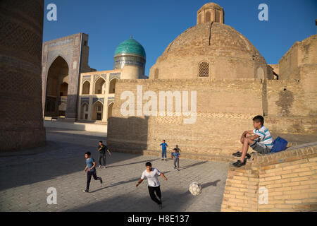 Jugendliche Kinder spielen Fußball, der von Sonnenuntergang in der antiken Stadt Buchara, Usbekistan - Reisefotos Seidenstraße Stockfoto