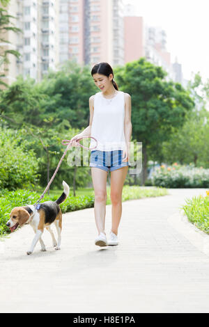 Junge chinesische Frau zu Fuß mit einem niedlichen Hund Stockfoto