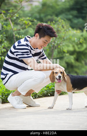 Junge Chinesin, die das Spiel mit einem niedlichen Hund Stockfoto