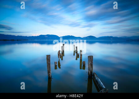 Hölzerne Pier oder Steg bleibt auf See Sonnenuntergang und Himmel Spiegelung auf dem Wasser. Langzeitbelichtung, Versilia Massaciuccoli See, Italien Stockfoto