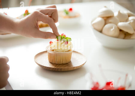 Nahaufnahme von weiblicher Hand Richtfest einen Cupcake mit Minze Stockfoto