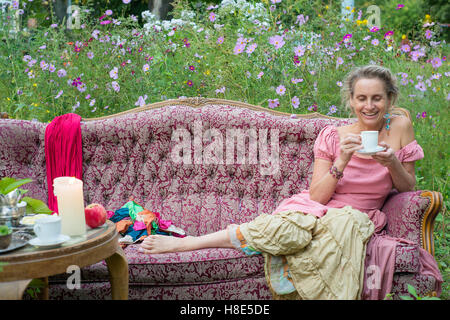 Frau sitzt auf der Couch in den Garten und Tee trinken Stockfoto