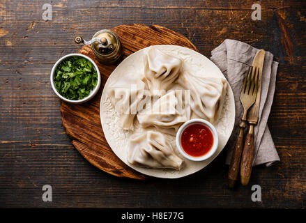 Georgische Knödel Khinkali mit Fleisch, Greens und Tomate, pikanter Sauce Satsebeli auf weißen Teller Stockfoto