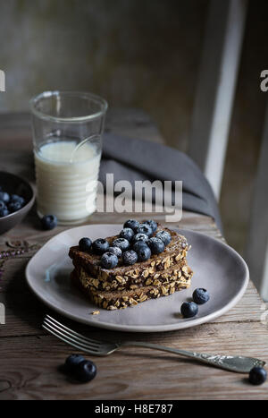 Frühstück mit Müsli, Brot und Blaubeeren auf Holztisch Stockfoto