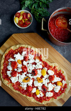 Geröstete Tomaten Pizza mit einer dünnen Olivenöl Crackerkruste.  Fotografiert auf schwarz/grau Hintergrund aus Draufsicht. Stockfoto