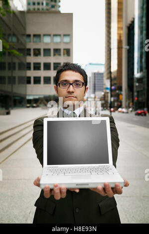 Geschäftsmann hält Laptop outisde Stockfoto