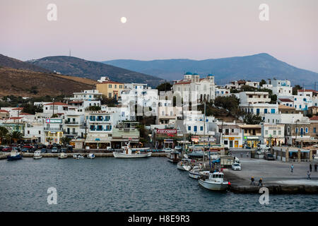 Ferry Wharf an Stadt von Gavrio auf der Insel Andros, Griechenland bei Sonnenuntergang mit Vollmond erhebt sich über. Stockfoto