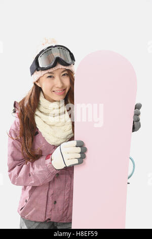 Junge japanische Frau trägt Snowboard Verschleiß auf weißem Hintergrund Stockfoto
