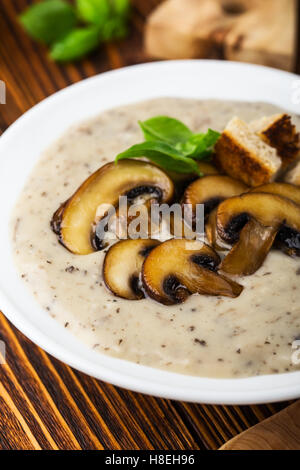 Köstliche hausgemachte Herbst Pilzsuppe mit gebratenen Pilzen in weißen Teller und Keramikschale mit frischen rohen Pilzen Stockfoto
