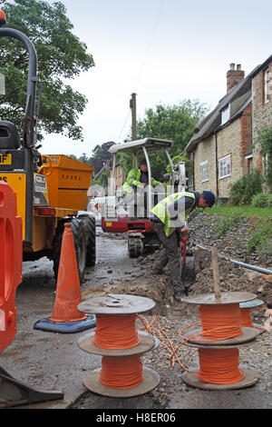 Arbeiter, die Installation von Kabeln für superschnellen Breitband in einem ländlichen Dorf Oxfordshire, UK. Trommeln der orange optisches Kabel zeigt. Stockfoto