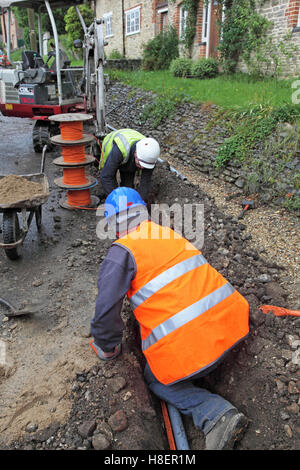 Arbeiter, die Installation von Kabeln für superschnellen Breitband in einem ländlichen Dorf Oxfordshire, UK. Trommeln der orange optisches Kabel zeigt. Stockfoto