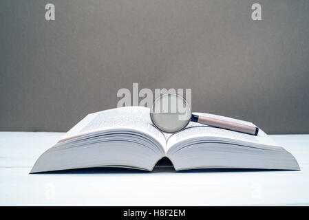 Lupe und leeres Buch auf einem Holztisch. Konzept der auf der Suche nach Antwort, Lösung oder wissen Stockfoto