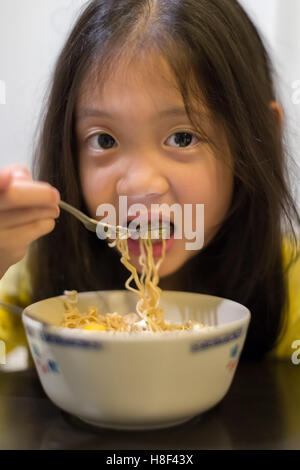 Hungriges Kind essen Nudeln oder chinesische Ramen. Stockfoto