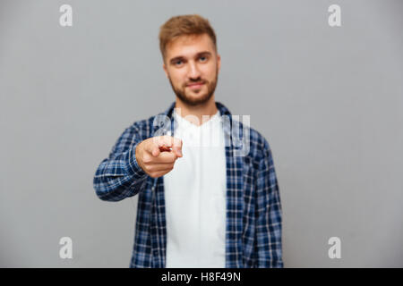 Porträt von einem gutaussehenden Mann Zeigefinger in die Kamera auf einem grauen Hintergrund isoliert Stockfoto