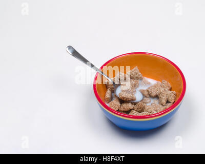 Weizen-Getreide und Milch in einer Schüssel mit Löffel Stockfoto