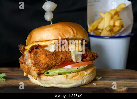 Beefburger und Brötchen mit Chips (Pommes) auf einem hölzernen Teller serviert. eine UK Stockfoto