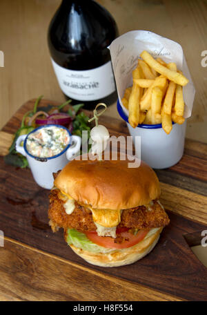 Beefburger und Brötchen mit Chips (Pommes) auf einem hölzernen Teller serviert. eine UK Stockfoto