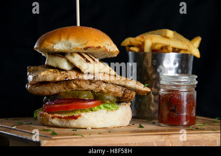 Einen Chicken-Burger mit Pommes Frites (Pommes frites) auf einer hölzernen Platte. eine UK-Essen Stockfoto