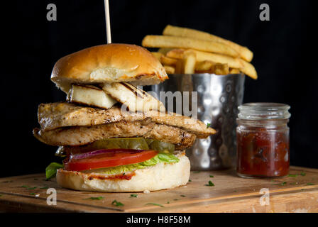 Einen Chicken-Burger mit Pommes Frites (Pommes frites) auf einer hölzernen Platte. eine UK-Essen Stockfoto