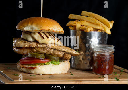 Einen Chicken-Burger mit Pommes Frites (Pommes frites) auf einer hölzernen Platte. eine UK-Essen Stockfoto