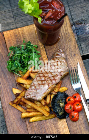 Steak & Chips mit Champignons und Tomaten auf einem hölzernen Teller serviert. eine UK-Essen-Küche Stockfoto