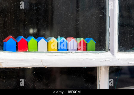 Reihe von kleinen bunten Strand Hütte Holzornamente sitzen auf Fensterrahmen Stockfoto