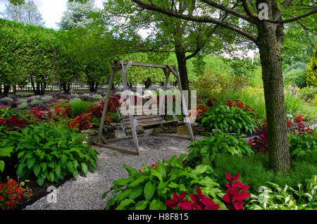 Holzschaukel Sitz im Pineland Garden mit Hostas und Coleus im Schatten Schotter Weg, neue Gloucester, Maine, USA Stockfoto