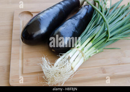 Aubergine mit Frühlingszwiebeln auf Schneidebrett Stockfoto