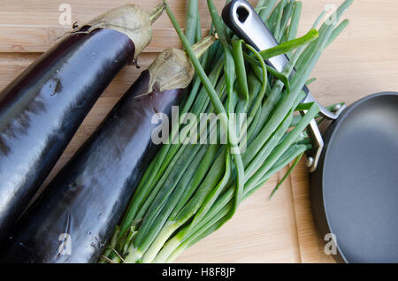 Aubergine mit Frühlingszwiebeln auf Schneidebrett Stockfoto