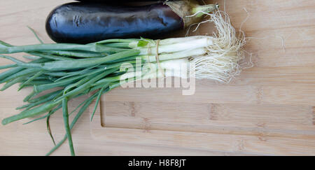 Aubergine mit Frühlingszwiebeln auf Schneidebrett Stockfoto