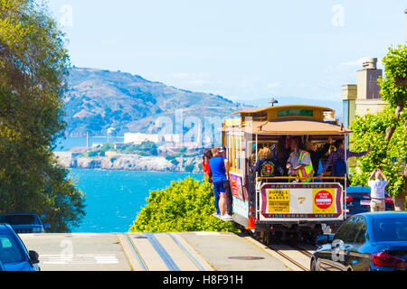 Seilbahn mit Touristen fahren außerhalb Annäherung an steilen Abgrund Kante am Gipfel des Hyde St mit fantastischen Blick auf Alcatraz Gefängnis, Stockfoto